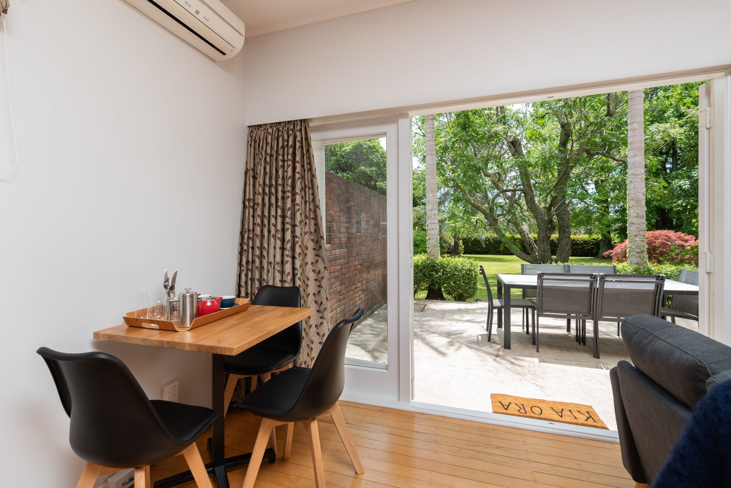 Indoor and outdoor dining with superb garden views from the Takahē suite at Pāteke Lodge.