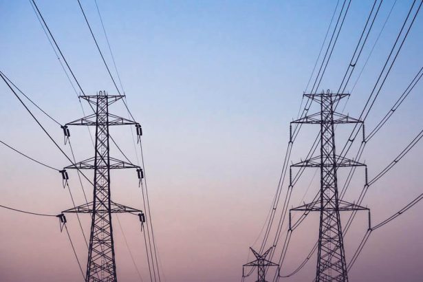 High voltage power pylons and lines against the dusk sky.