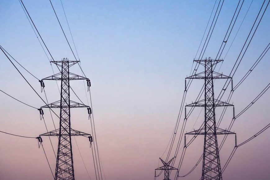 High voltage power pylons and lines against the dusk sky.