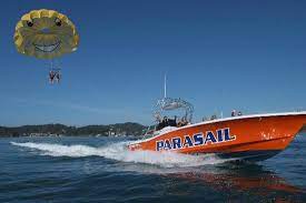 Two people parasailing behind a boat on the Bay of Islands, New Zealand.